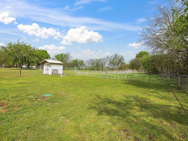 view of yard featuring a storage unit, fence, an outbuilding, and a rural view