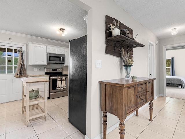 kitchen featuring a textured ceiling, white cabinets, light tile patterned flooring, and stainless steel appliances