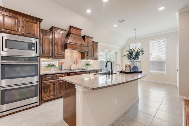 9836 Arctic Dr, Frisco, TX 75035 - kitchen featuring a sink, stainless steel appliances, light stone counters, custom exhaust hood, and light tile patterned floors