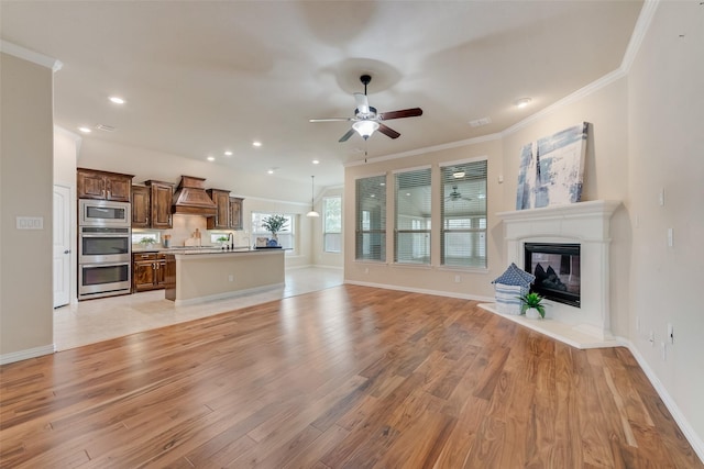 9836 Arctic Dr, Frisco, TX 75035 - unfurnished living room featuring ornamental molding, ceiling fan, light wood-style floors, a glass covered fireplace, and baseboards