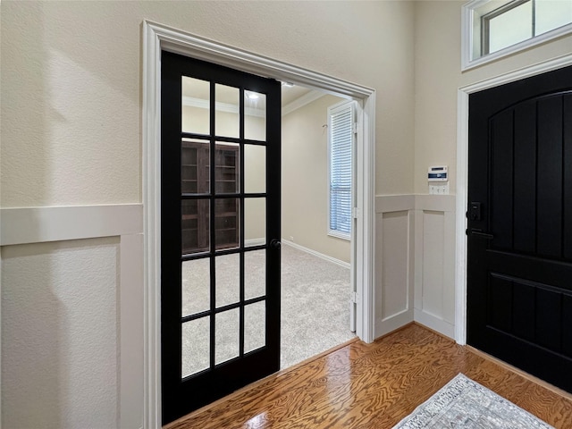 foyer with wainscoting, a healthy amount of sunlight, and wood finished floors