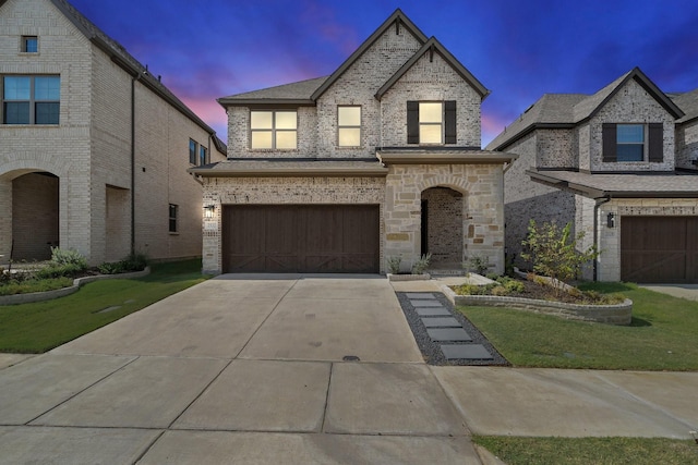 french provincial home with brick siding, a front yard, concrete driveway, and an attached garage