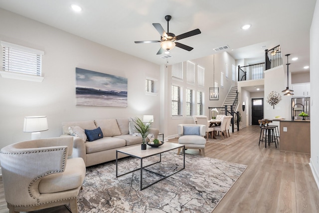 living room featuring stairway, visible vents, a healthy amount of sunlight, and light wood finished floors