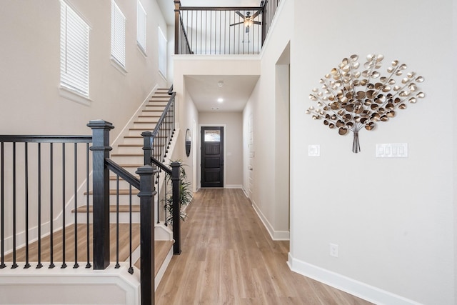 entryway featuring a towering ceiling, wood finished floors, stairway, and baseboards