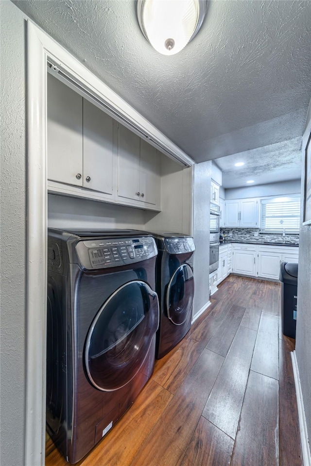 6110 Caracas Dr, Dallas, TX 75232 - laundry room featuring separate washer and dryer, a textured ceiling, baseboards, cabinet space, and dark wood-style flooring