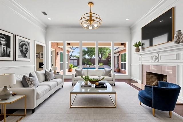 2 La Costa Ct, Frisco, TX 75034 - living room with crown molding, a chandelier, a fireplace, and wood finished floors
