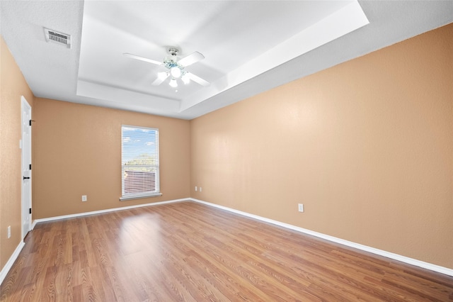 4730 Parkhaven Dr, Garland, TX 75043 - unfurnished room with a raised ceiling, light wood-style flooring, baseboards, visible vents, and ceiling fan