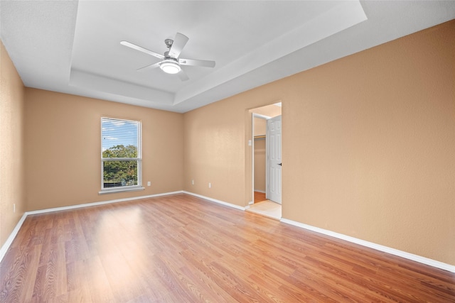 4730 Parkhaven Dr, Garland, TX 75043 - empty room with a ceiling fan, a tray ceiling, light wood-style floors, and baseboards