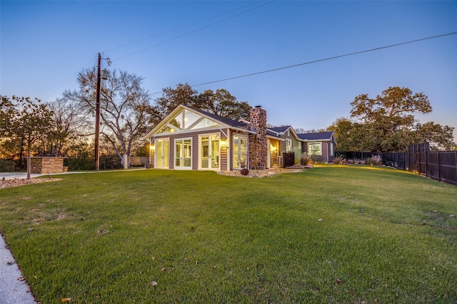 147 Cotton Franklin Rd, Gordonville, TX 76245 - back of house at dusk featuring a lawn, fence, and a chimney