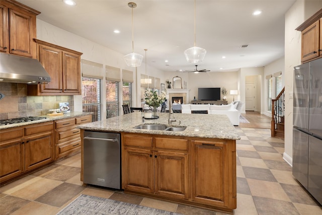 1715 San Jacinto Dr, Allen, TX 75013 - kitchen with stainless steel appliances, under cabinet range hood, a sink, a center island with sink, and brown cabinets