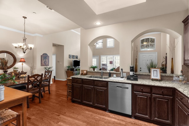 kitchen with dark brown cabinets, a sink, dishwasher, arched walkways, and light wood-style flooring