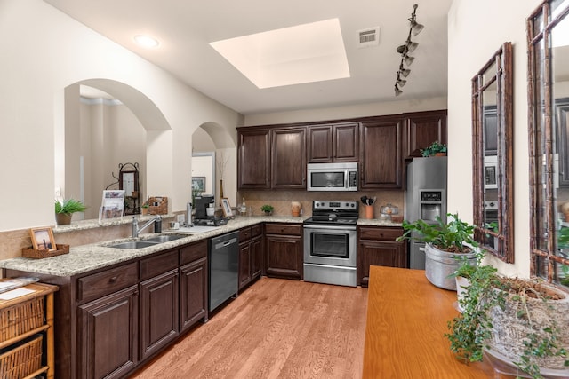 kitchen with stainless steel appliances, visible vents, a sink, light wood-style floors, and dark brown cabinetry