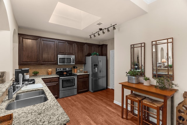 kitchen with dark brown cabinets, a sink, a skylight, appliances with stainless steel finishes, and visible vents