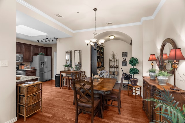 dining room featuring crown molding, wood finished floors, arched walkways, an inviting chandelier, and visible vents