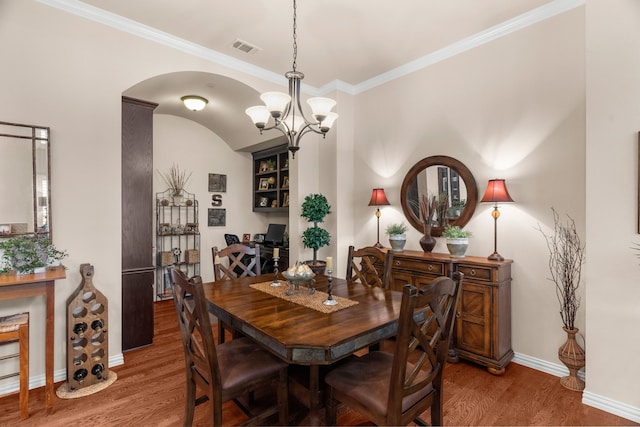 dining area featuring wood finished floors, visible vents, crown molding, baseboards, and a chandelier