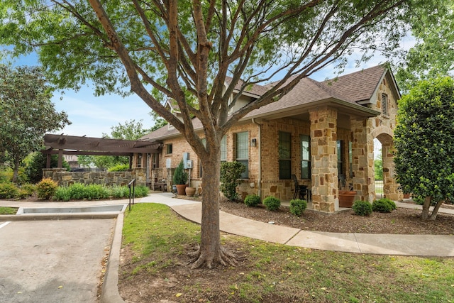 view of front of home with stone siding, a pergola, and a shingled roof