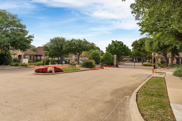 view of street featuring a gate, a gated entry, curbs, and sidewalks