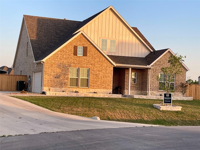 131 Clearwater Ct, Rhome, TX 76078 - view of front of property featuring board and batten siding, a front yard, fence, brick siding, and a garage