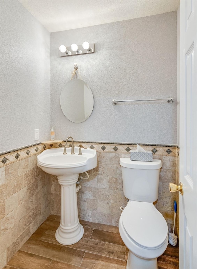 bathroom featuring tile walls, toilet, wainscoting, and wood tiled floor