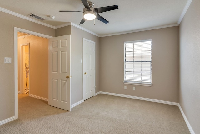 unfurnished bedroom featuring crown molding, visible vents, baseboards, and light carpet