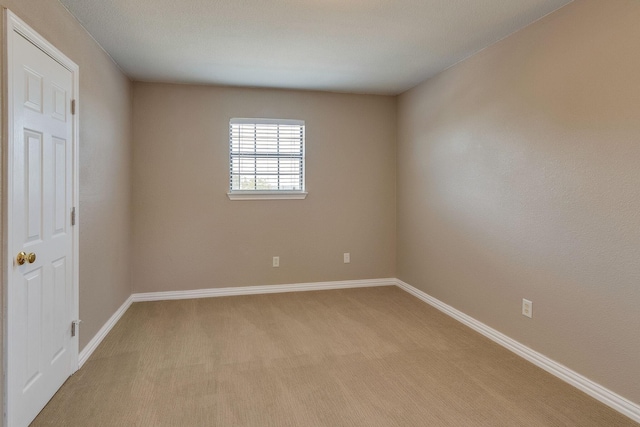 spare room with light carpet and baseboards