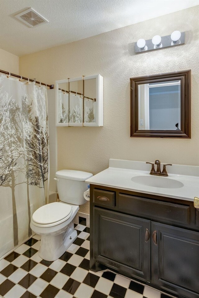 bathroom featuring vanity, tile patterned floors, a textured ceiling, toilet, and visible vents