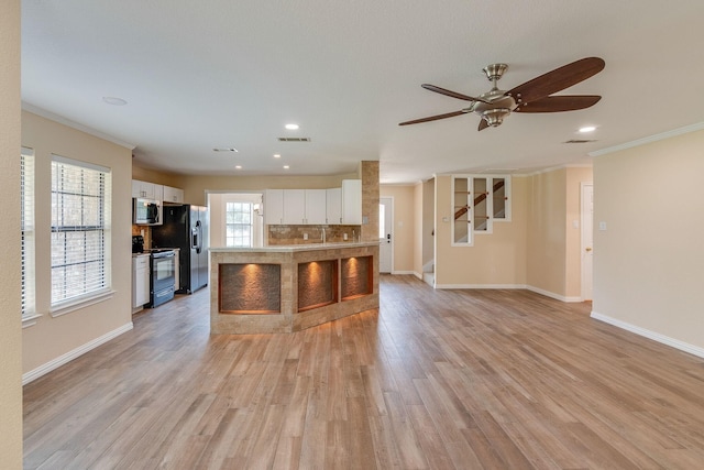 kitchen with tasteful backsplash, electric range, stainless steel microwave, and light wood-style floors