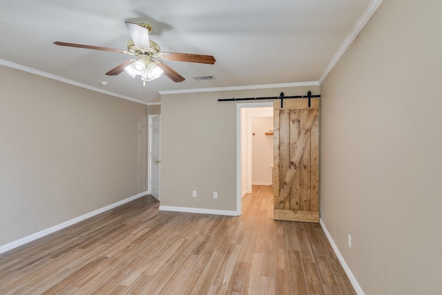 unfurnished room featuring baseboards, light wood-type flooring, crown molding, a barn door, and ceiling fan