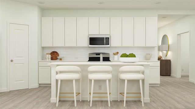 kitchen featuring light countertops, stove, stainless steel microwave, a center island, and backsplash