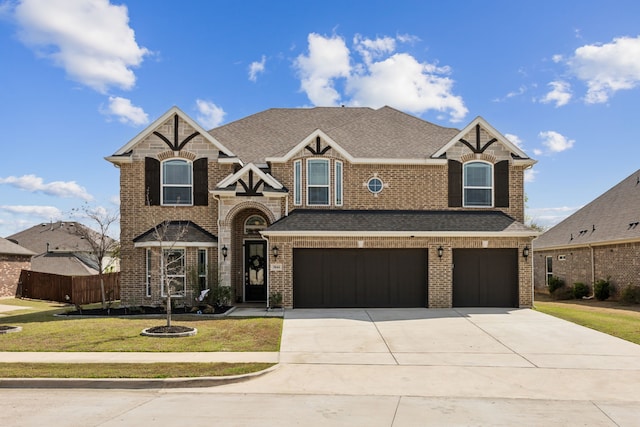 view of front facade with fence, an attached garage, concrete driveway, a front yard, and brick siding
