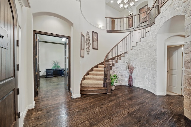 entryway with a towering ceiling, wood finished floors, and stairway