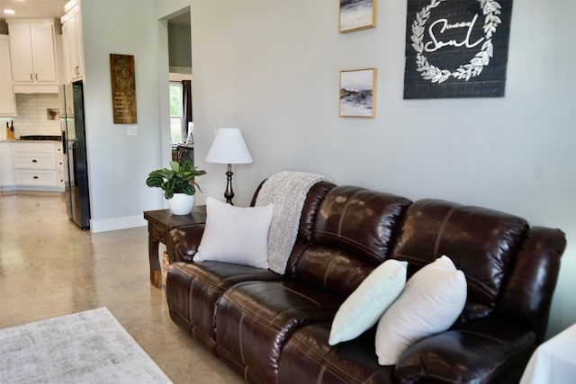living area featuring baseboards and finished concrete floors