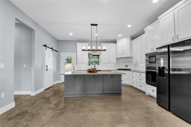 kitchen with a barn door, baseboards, white cabinets, concrete floors, and stainless steel appliances