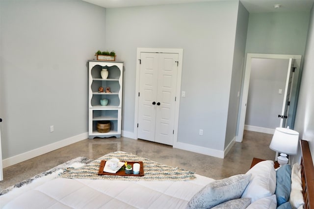 bedroom featuring baseboards, a closet, and concrete floors