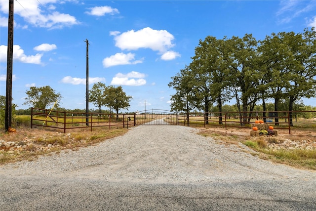 view of street featuring a gate, a rural view, and gravel driveway