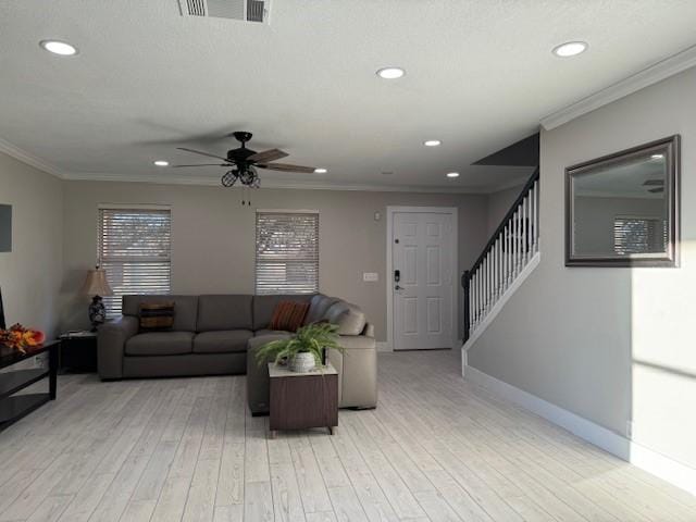 living area featuring stairs, light wood-type flooring, ornamental molding, baseboards, and visible vents