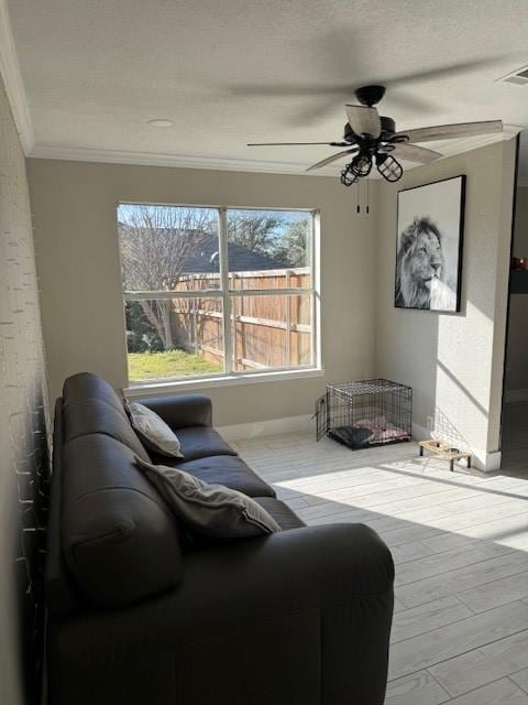living room with ornamental molding, a textured ceiling, visible vents, ceiling fan, and wood finished floors