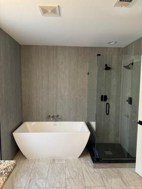 bathroom featuring marble finish floor, visible vents, a soaking tub, and a shower stall