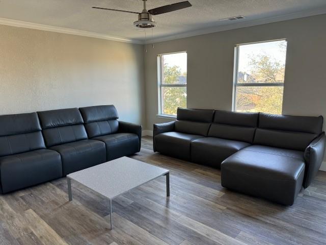 living area featuring a textured ceiling, visible vents, crown molding, wood finished floors, and a ceiling fan
