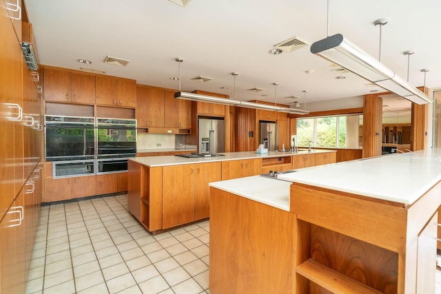 kitchen featuring light countertops, a skylight, brown cabinets, a sink, and light tile patterned floors