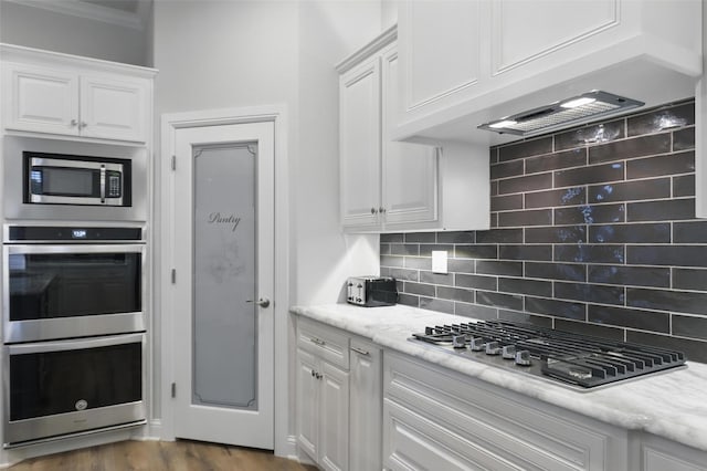 1011 Cardinal Cv, Graford, TX 76449 - kitchen with stainless steel appliances, white cabinetry, backsplash, crown molding, and dark wood-style flooring