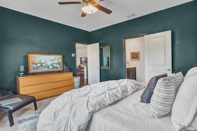 bedroom with ensuite bathroom, visible vents, carpet, and a ceiling fan