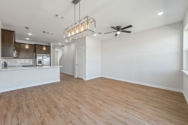 kitchen featuring open floor plan, backsplash, a ceiling fan, dark brown cabinetry, and appliances with stainless steel finishes