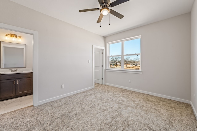 unfurnished bedroom featuring a sink, light carpet, baseboards, and ensuite bath