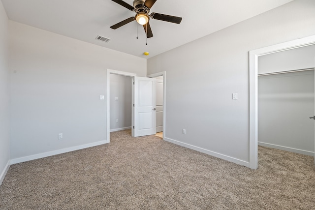 unfurnished bedroom with a closet, visible vents, baseboards, a walk in closet, and light colored carpet