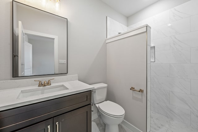 bathroom with toilet, vanity, baseboards, and a walk in shower