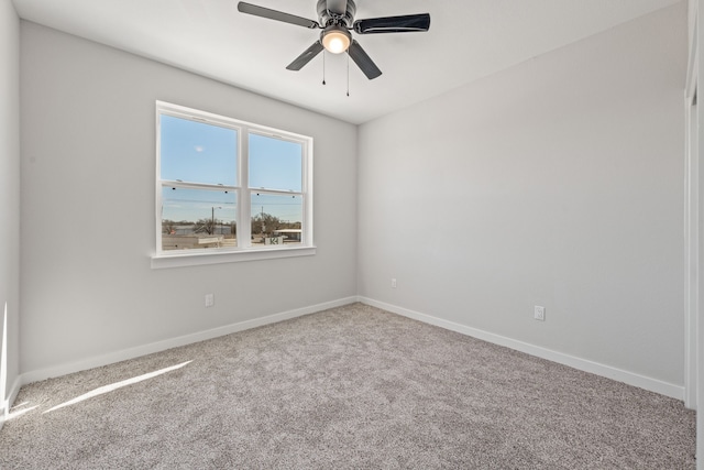 carpeted spare room featuring baseboards and ceiling fan