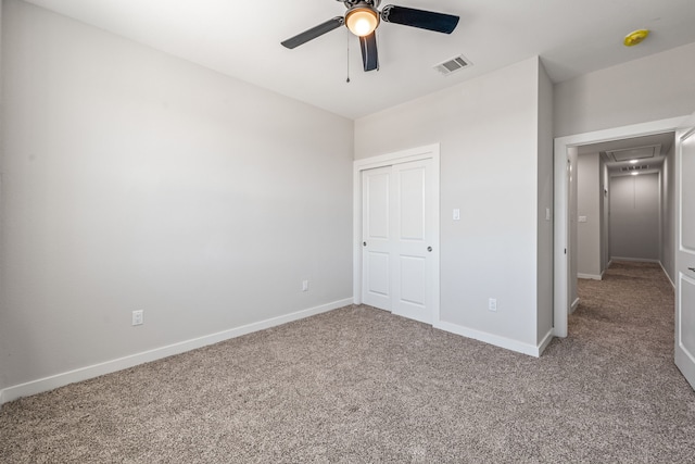unfurnished bedroom with carpet flooring, attic access, baseboards, visible vents, and ceiling fan