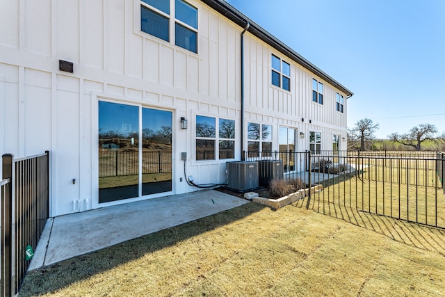 rear view of house featuring fence, cooling unit, and board and batten siding