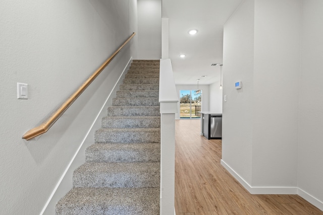 stairs featuring baseboards, wood finished floors, and recessed lighting